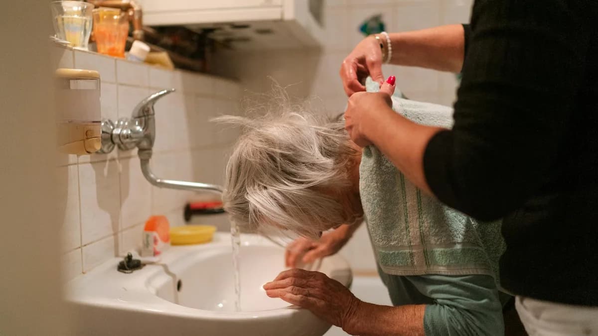 Caregiver helping an older adult at a bathroom sink for home safety after stroke